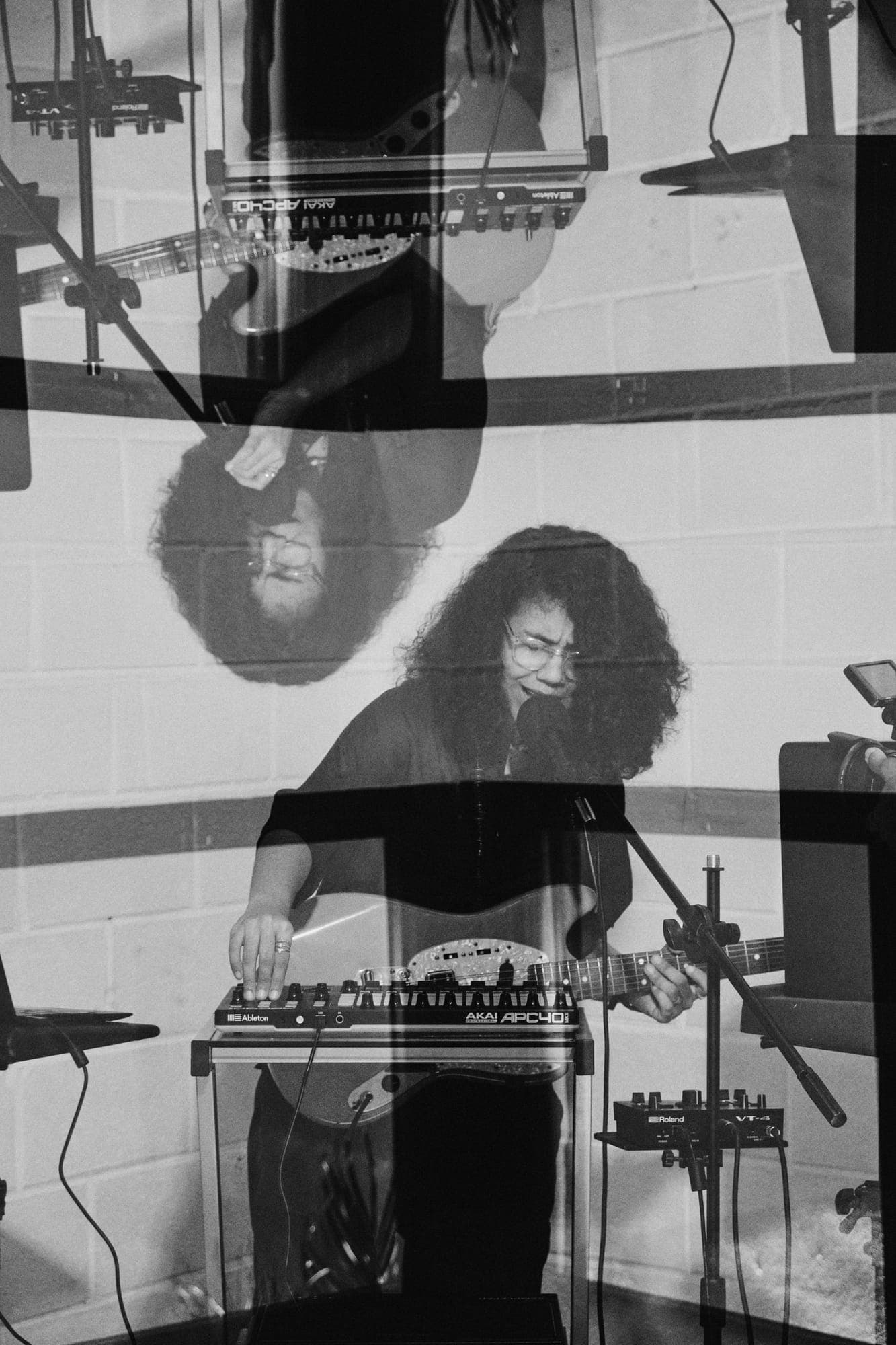 Doble exposición del rodaje de Raíces: cantando al micrófono mientras toca la guitarra sobre un controlador Akai APC40.